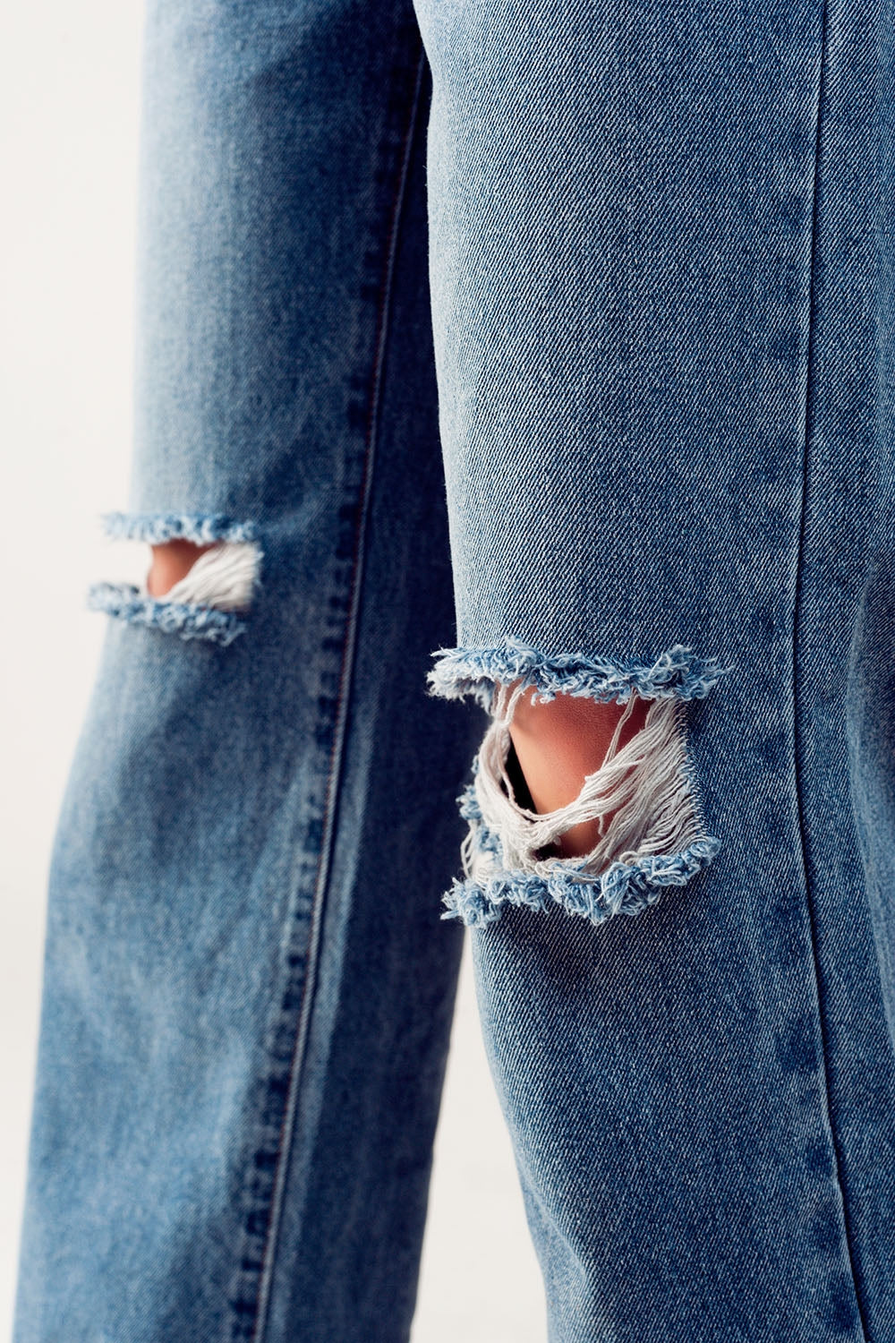 Distressed straight leg jean in medium denim