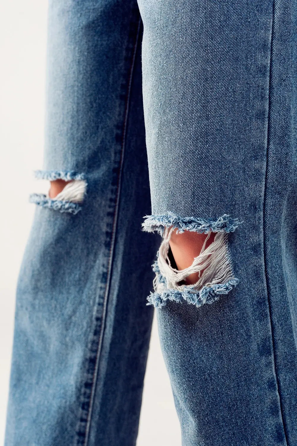 Distressed straight leg jean in medium denim