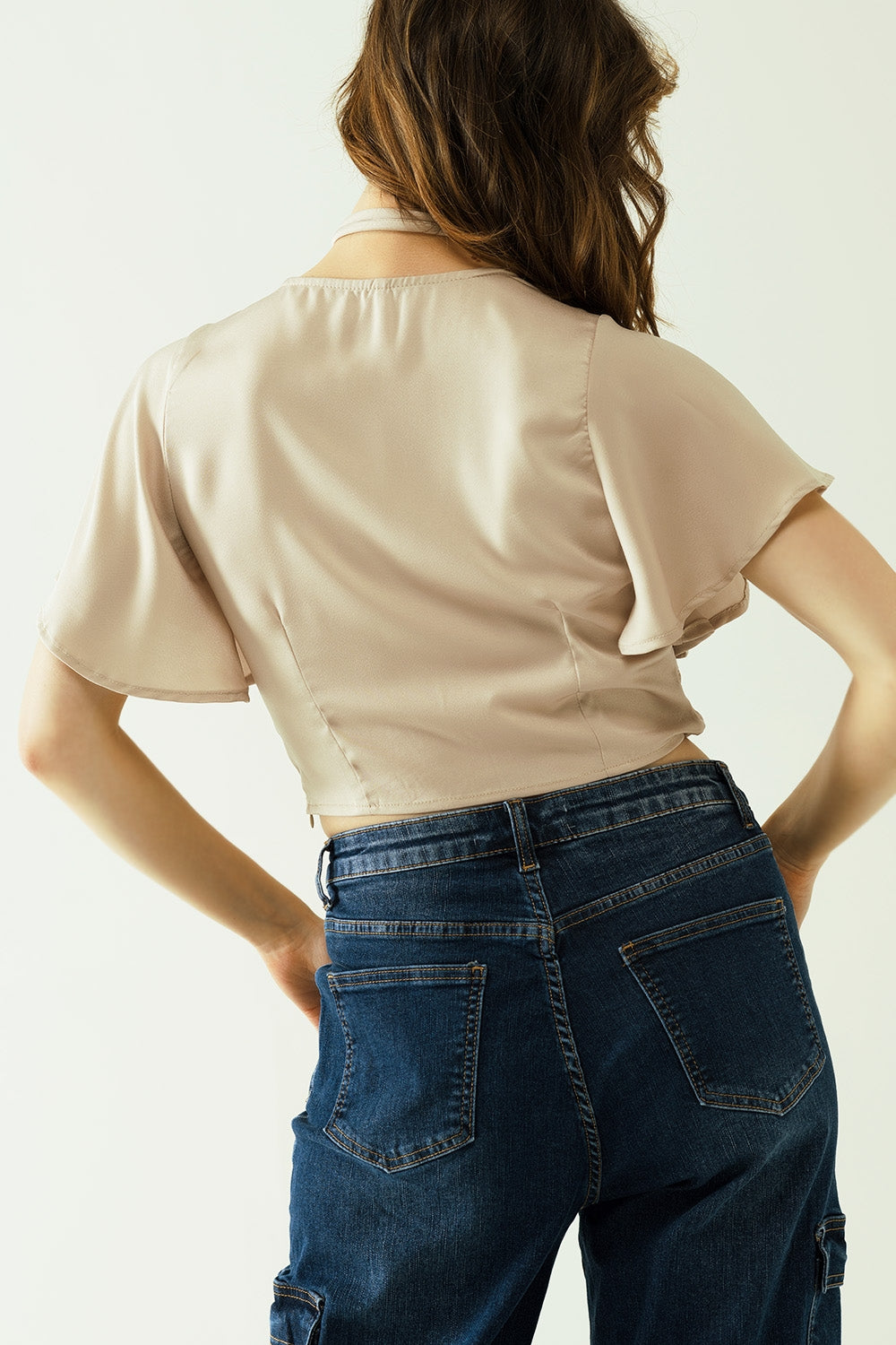 Beige V-neck crop top with short sleeves and a flower detail on the neck