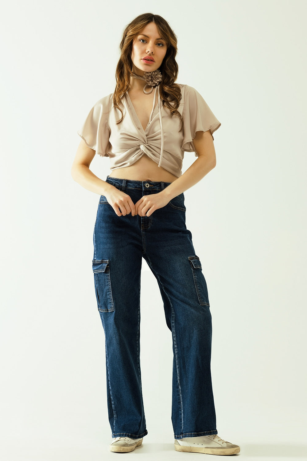 Beige V-neck crop top with short sleeves and a flower detail on the neck