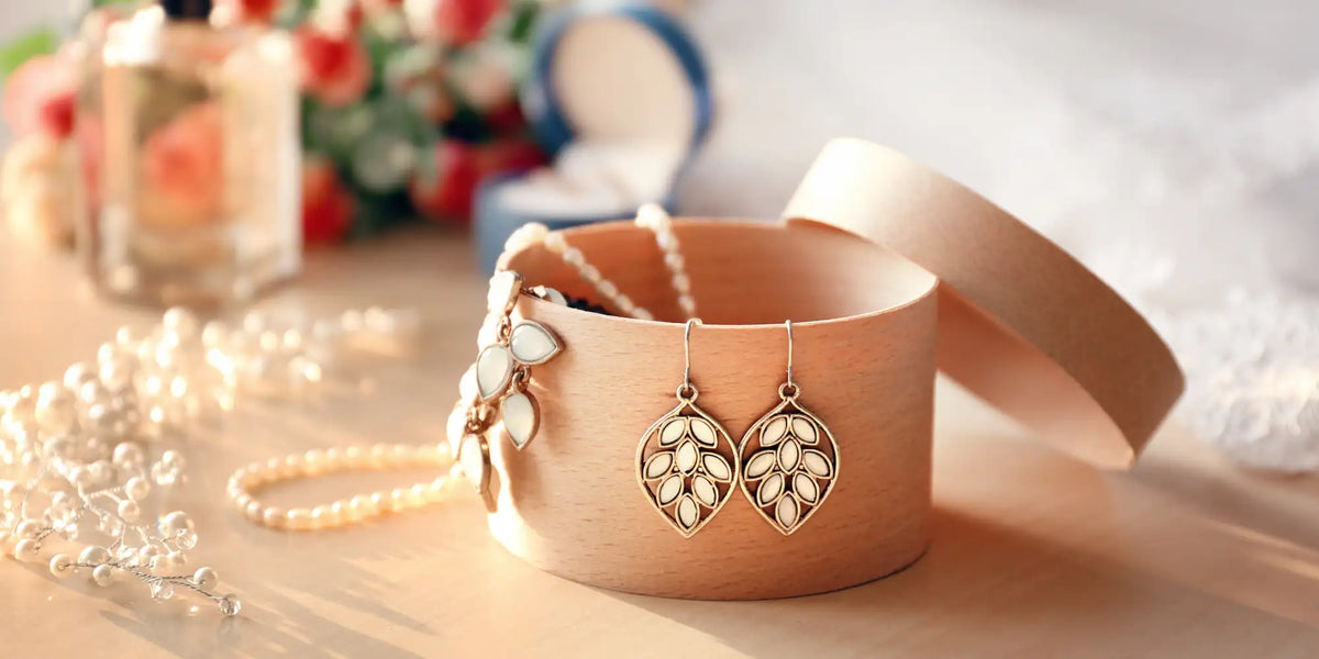 Gold leaf-shaped earrings with intricate detailing and pearl accents.