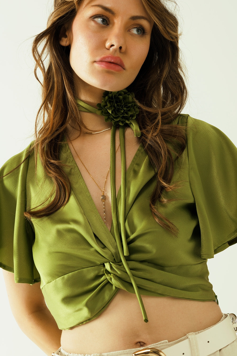 Green V-neck crop top with short sleeves and a flower detail on the neck