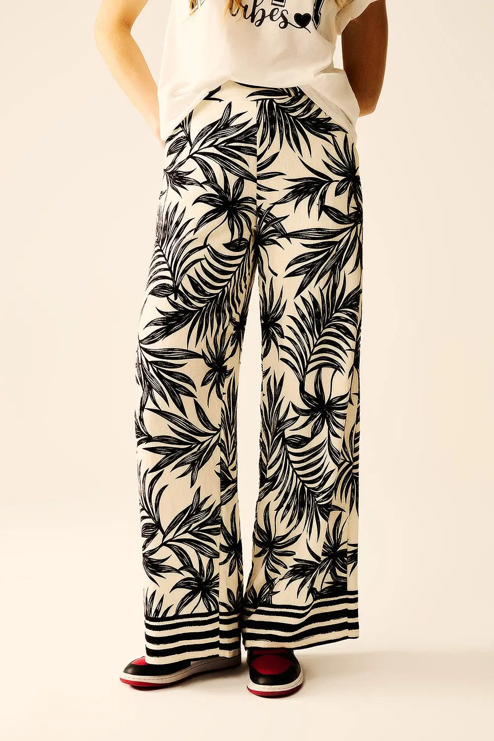 Pantalon à jambes larges en blanc avec détails floraux en noir - Pantalons