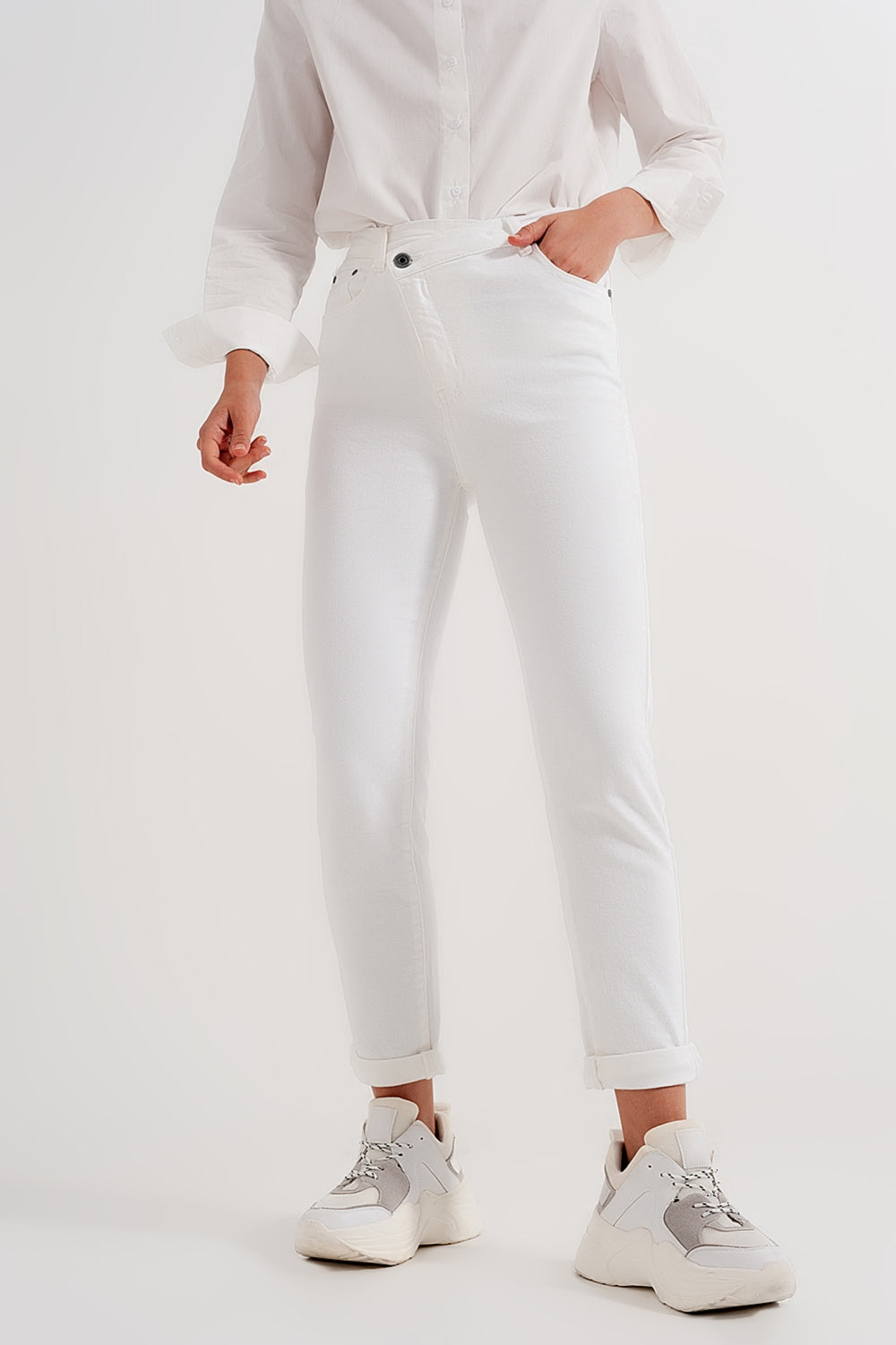 Slim jeans with asymmetric button in cream